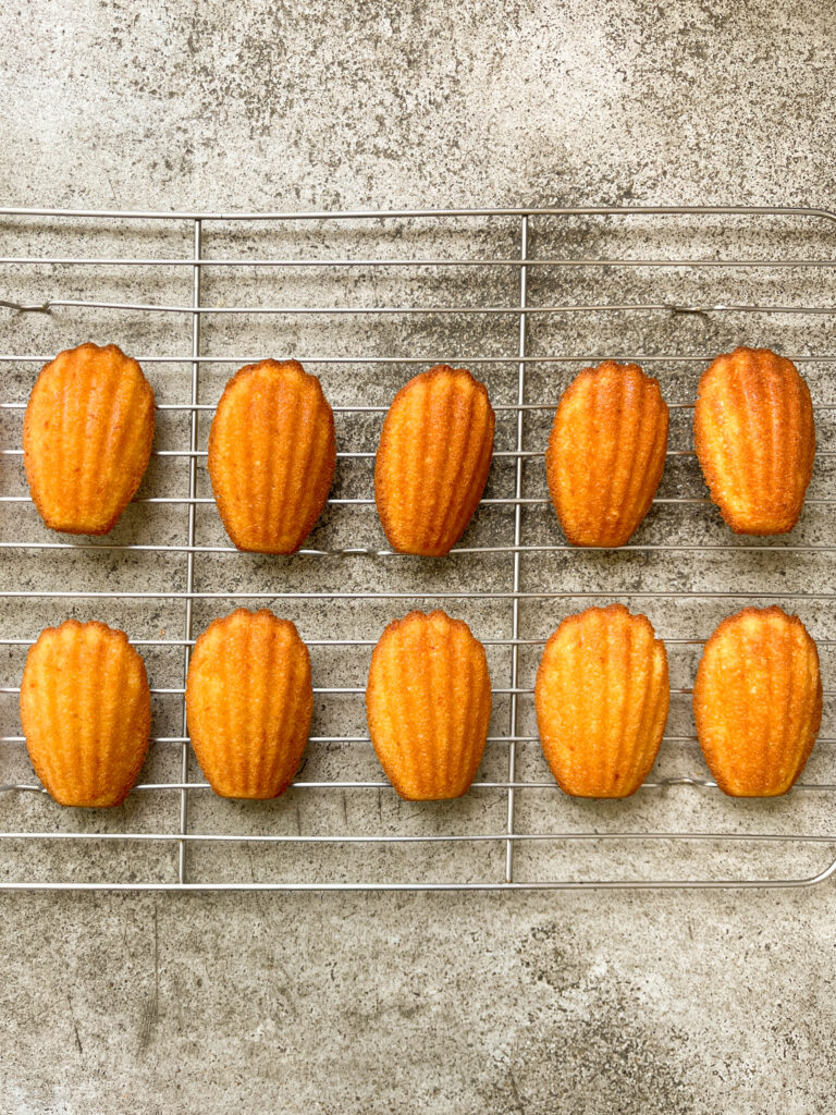 Orange Madeleines fresh out of the oven on a cooling rack