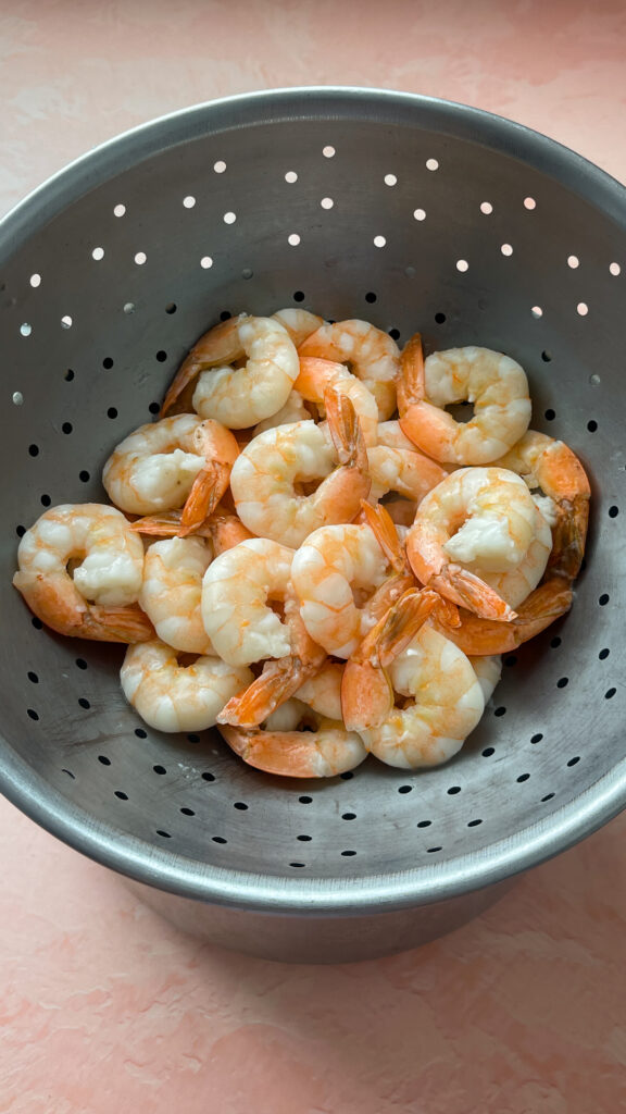 Shrimp that has been parboiled, and is draining in a colander