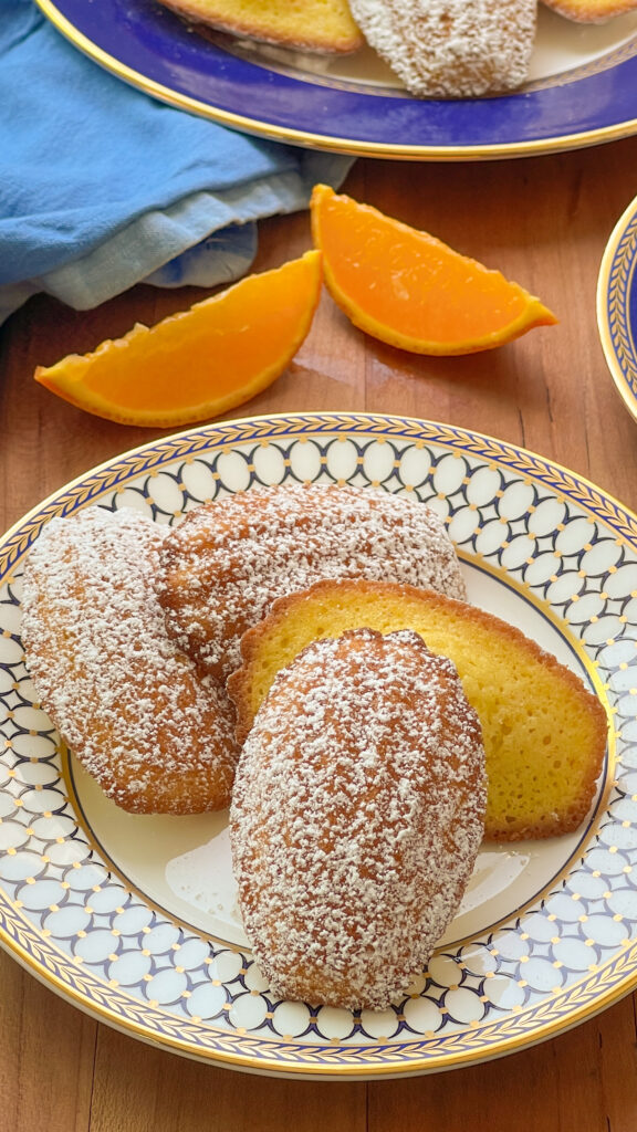 Madeleines with orange slices on a wooden cutting board