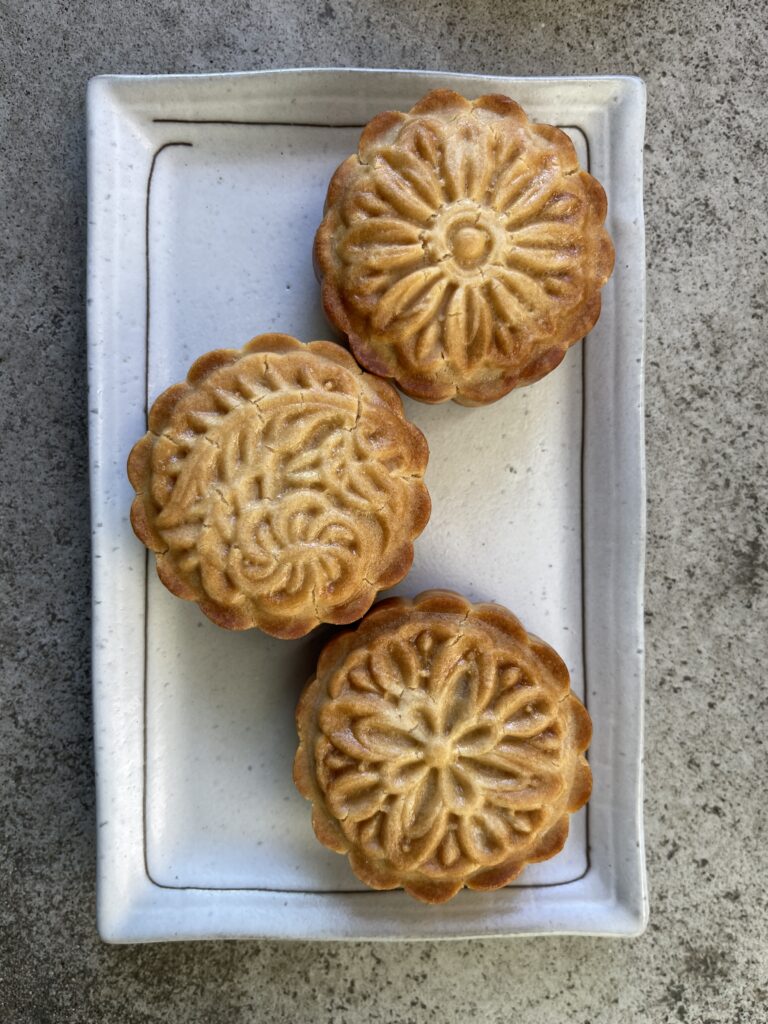 three honey pistachio mooncakes on a rectangular platter viewed from above