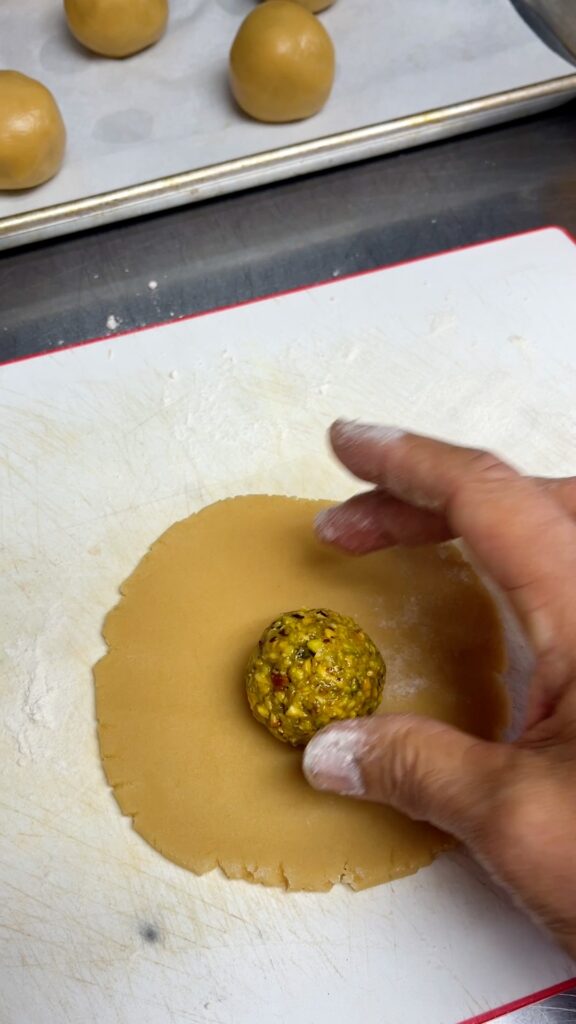 a ball of pistachio and honey filling placed on a rolled out 4" disc of dough