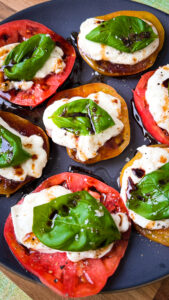 Insalata Caprese with a vibrant photo that captures the lush red of organic heirloom tomatoes, the pristine white of buffalo mozzarella, and the fresh green of basil leaves, all artfully drizzled with golden olive oil and rich balsamic vinegar dressing.